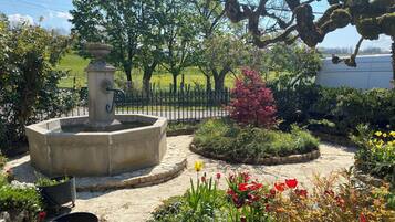 Un jardin agrémenté d’une fontaine, de différentes plantes et d’une zone dallée.