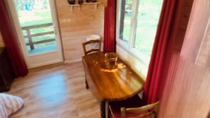 Ein Holztisch mit Stühlen, ein Fenster mit Vorhängen und eine Tür, die nach draußen führt.