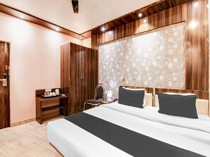 A modern hotel room with a large bed, a wardrobe, a bedside table with a lamp, and a decorative wall panel. - Deluxe Collection O Park Circus (Kolkata)
