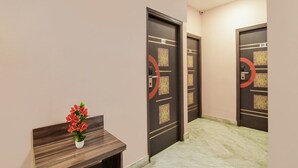 A hallway with two doors, each marked with a number, and a small table with a potted plant. - Deluxe Collection O Park Circus (Kolkata)