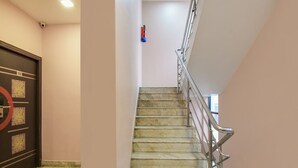 A staircase with a handrail, a door with a number plate, and a security camera. - Deluxe Collection O Park Circus (Kolkata)