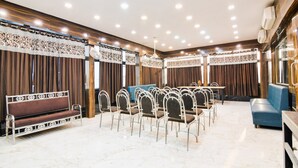A conference room with a long table, chairs, a sofa, and a patterned wall. - Deluxe Collection O Park Circus (Kolkata)