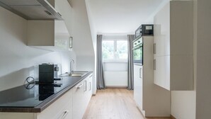 Een moderne keuken met een zwart aanrecht, witte kastjes en een raam met gordijnen.