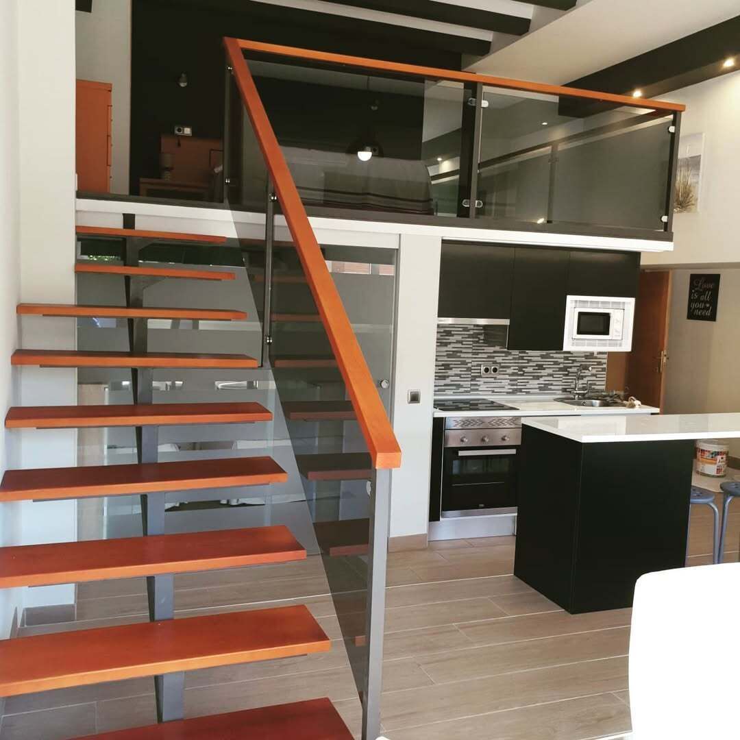 A modern kitchen with a microwave, oven, and a glass staircase leading to an upper level.