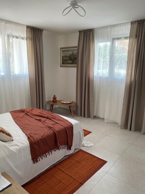 Ein Schlafzimmer mit einem Bett, einem kleinen Tisch mit einer Vase und einem Bild an der Wand.