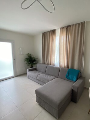 Ein Wohnzimmer mit einer Couch, einem Couchtisch, einer Zimmerpflanze und einer Schiebetür.