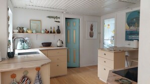 Eine Küche mit blauer Tür, Holzschränken und einer Kaffeemaschine.