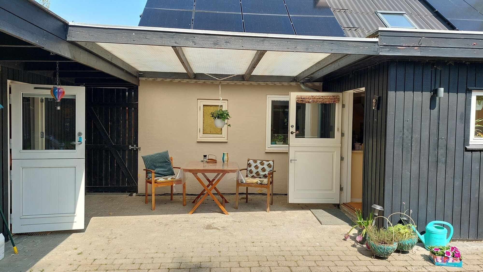 A covered patio with a table and chairs, a door, and a window.