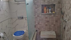 A bathroom with a shower, toilet, and a small shelf with toiletries. - COTE (Djerba - Houmt Souk)