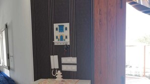 A room with a white dresser, a blue sofa, a wooden door, and a wall-mounted electrical panel. - COTE (Djerba - Houmt Souk)
