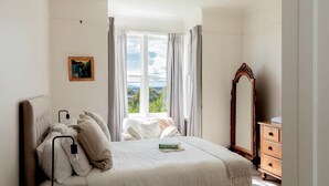 A bedroom with a bed, a dresser, a mirror, and a window with curtains.
