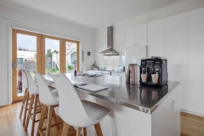 A modern kitchen with a central island, white cabinetry, and a coffee machine.