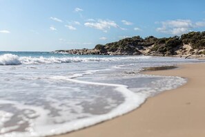 A beach with waves, a sandy shore, and rocky cliffs.