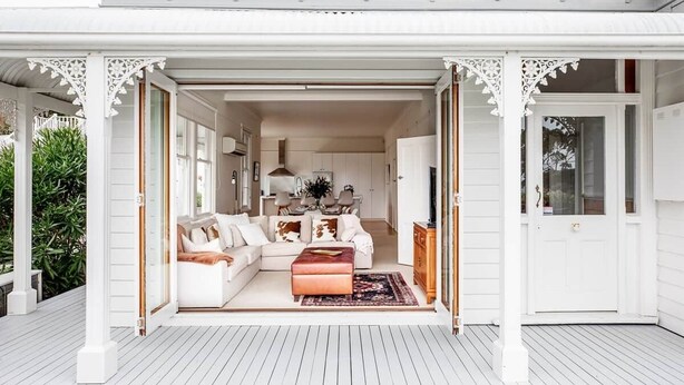 An open-plan living area with a sofa, ottoman, and dining table.