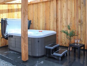 Ein Whirlpool mit Stufen, ein kleiner Tisch mit Gläsern und ein Blumentopf.