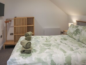 Ein Schlafzimmer mit einem Bett, einem Holzschrank und einem an der Wand befestigten Regal.