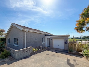 Eingeschossiges Haus mit Garage, einer kleinen Veranda und einem gepflegten Garten.