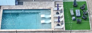 Ein Swimmingpool mit Rutsche, umgeben von Liegestühlen und einer kleinen Liegefläche.