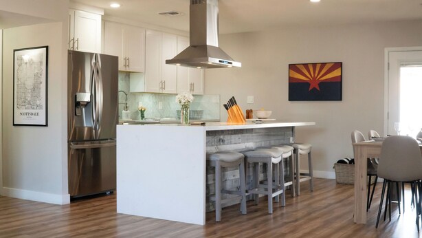 A modern kitchen with a central island, stainless steel appliances, and a bar area with stools. - 4-bdrm home with 2 Master Suites & Heated Pool minutes from Old Town Scottsdale (Scottsdale)