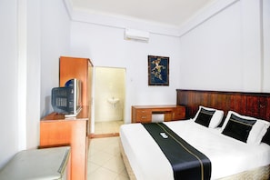 A hotel room with a bed, a desk with a computer, a wooden cabinet, a sink, and a framed picture on the wall. - Stylish Double Suite Escape W/ Free Wifi (Kedonganan)