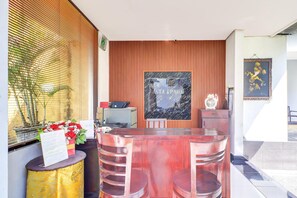 A reception area with a wooden panel wall, a marble-framed sign, a reception desk, and a plant.
