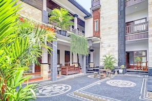 A courtyard with a patterned floor, potted plants, and a wooden bench. - Stylish Double Suite Escape W/ Free Wifi (Kedonganan)