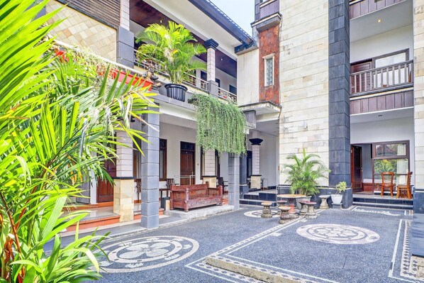A courtyard with a patterned floor, potted plants, and a wooden bench.