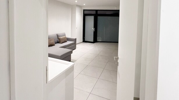 Een modern interieur met een bank, een tafeltje en een schuifdeur naar een andere kamer.