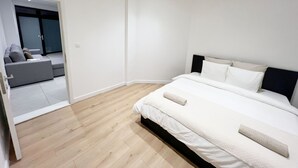 Een slaapkamer met een bed, een slaapbank en een deur naar een andere kamer.