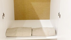 Een witte kast met een bruin ophangplank, houten kleerhangers en een opgerolde beige handdoek.