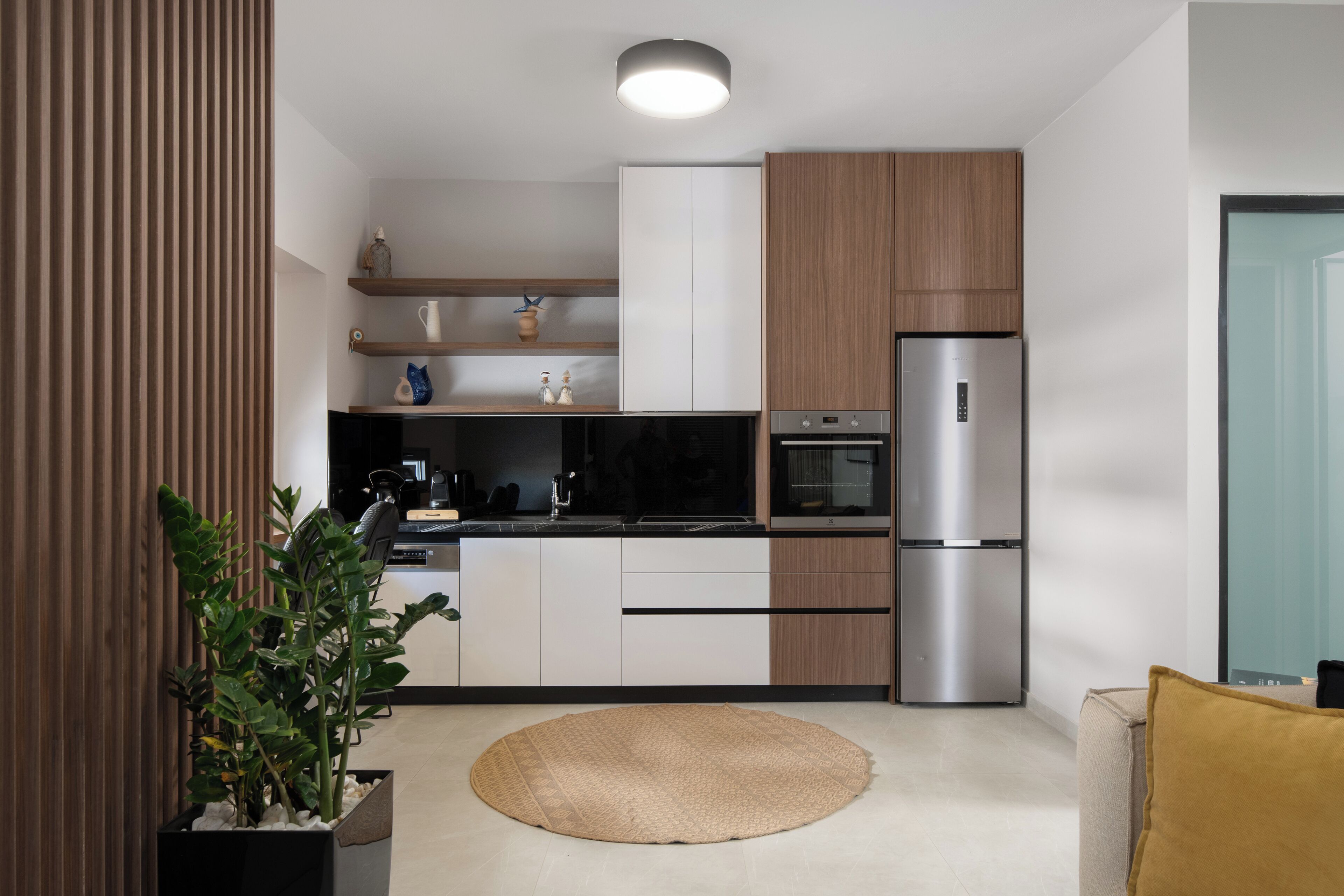 Una cocina moderna con horno empotrado, refrigerador de acero inoxidable y armarios de madera.