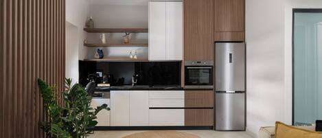 Una cocina moderna con horno empotrado, refrigerador de acero inoxidable y armarios de madera.