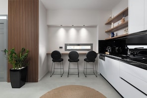 Eine moderne Küche mit weißen Schränken, schwarzen Arbeitsplatten und drei schwarzen Barhocker.