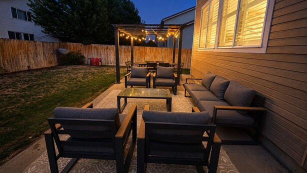 En uteplats med en pergola, sittplatser och ljusslingor.