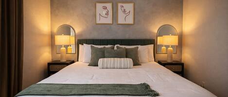 A hotel room with a large bed, two bedside tables with lamps, and two framed pictures on the wall.