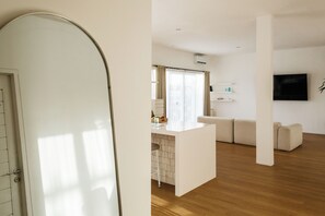 A modern living room with a sofa, a coffee table, and a TV mounted on the wall. - New 2BR Apartment near Dreamland Beach (Kuta)