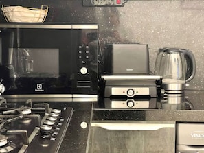 Eine Küche mit Mikrowelle, Herd, Kaffeemaschine und Wasserkocher.
