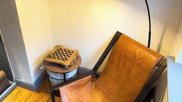 Une chaise avec un siège et un dossier en cuir, une petite table avec un plateau à carreaux et une lampe de bureau noire.