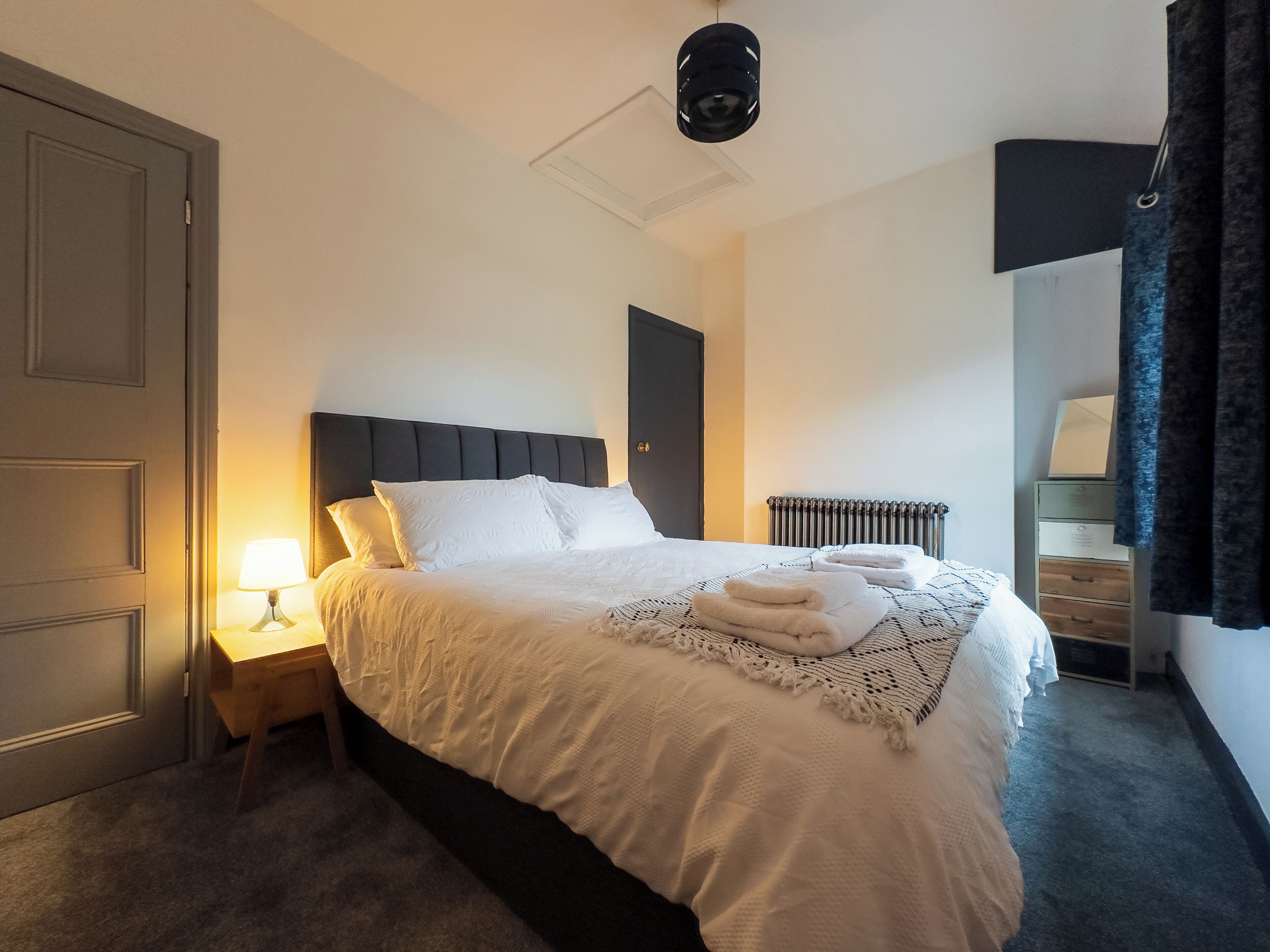 Een netjes ingerichte hotelkamer met een bed, bedlamp en een radiator.