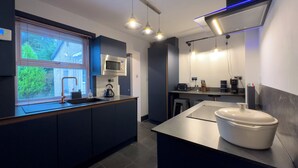 Una cocina moderna con microondas integrado, hervidor y una isla grande con pileta.