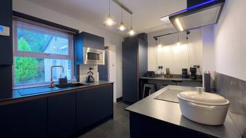 Une cuisine moderne équipée d’un four à micro-ondes encastré, d’une bouilloire et d’un grand îlot central avec un évier.