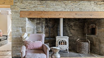 A cozy room with a stone fireplace, a comfortable armchair, and a small white stove.