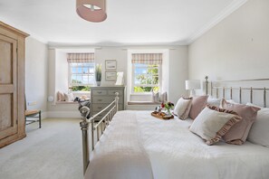 Une chambre à coucher comprenant un lit, un coin fenêtre aménagé en siège, une commode et une chaise.