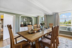 Un coin repas avec une table en bois, des chaises et une fenêtre agrémentée de rideaux.