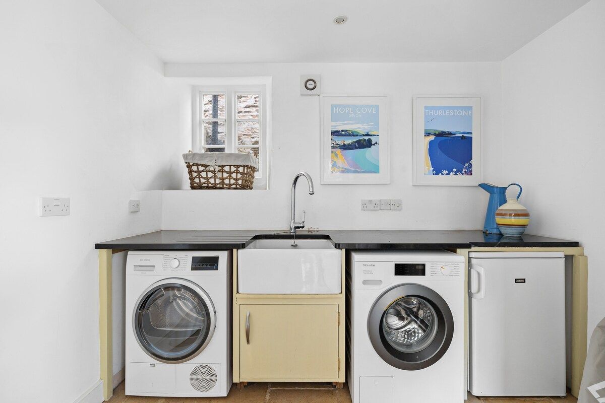 Un espace buanderie compact comprenant un lave-linge, un sèche-linge et un petit meuble de rangement.
