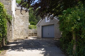 Un bâtiment en pierre doté d’une porte de garage, entouré de verdure.