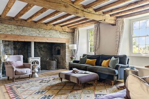 Une pièce rustique avec des poutres apparentes, une cheminée en pierre, un canapé et un tapis à motifs.