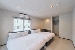 Quarto de hotel moderno com uma cama grande, uma escrivaninha, uma cadeira e uma janela.