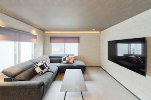 Una sala de estar moderna con un sofá modular, un televisor de pantalla plana y una mesa de centro minimalista.
