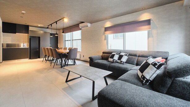 A modern living room with a sofa, a coffee table, and a dining area with chairs. - Sauna & Villa Yu to Yo (Chuo-ku, Sapporo City)